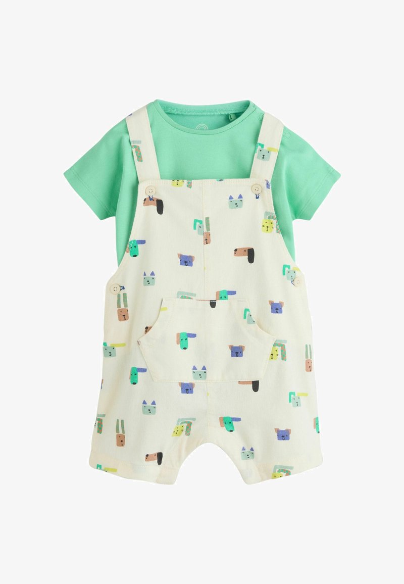 Camiseta verde de manga corta combinada con un peto color crema que presenta divertidos dibujos animados de animales en colores y un bolsillo delantero.