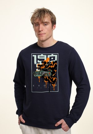Marineblå sweatshirt med et grafisk print af en klassisk bil med orange og sort malingstænk. Fremstillet i bomuldsmateriale med rund hals.