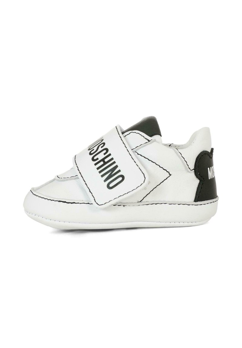 Scarpine per bambini in pelle bianca con dettagli neri, dotate di una fascia in Velcro etichettata "MOSCHINO" e un design con punta arrotondata.