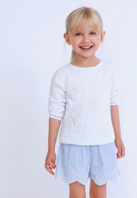 Felpa bianca con applicazioni a forma di farfalla, abbinata a pantaloni corti blu e bianchi a righe con bordino in pizzo all'orlo.