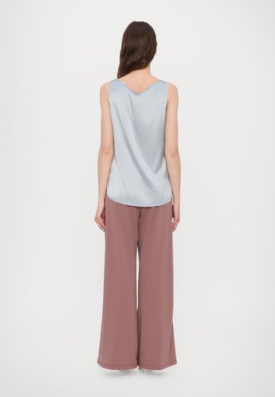 Top de satin azul claro com decote em V, combinado com calças largas de cintura alta em rosa antigo, com uma textura suave e acabamento na bainha.