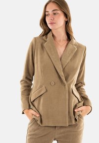 Blazer in corduroy khaki con design doppiopetto, rever a scudo, tasche laterali e tessuto testurizzato.