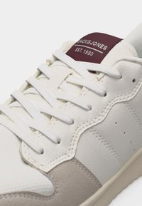 Άσπρο δερμάτινο αθλητικό παπούτσι με μπεζ σουέντ λεπτομέρειες, άσπρα κορδόνια και μπορντώ ετικέτα στη γλώσσα με την επιγραφή "JACK&JONES EST. 1990".