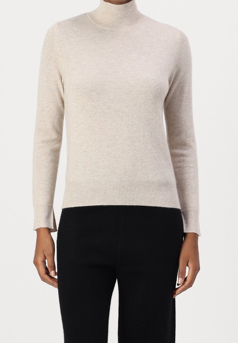 Beige polotröja i mjukt stickat material, med långa ärmar och ribbad nederkant. Designad med sidospjälor för rörelsefrihet.