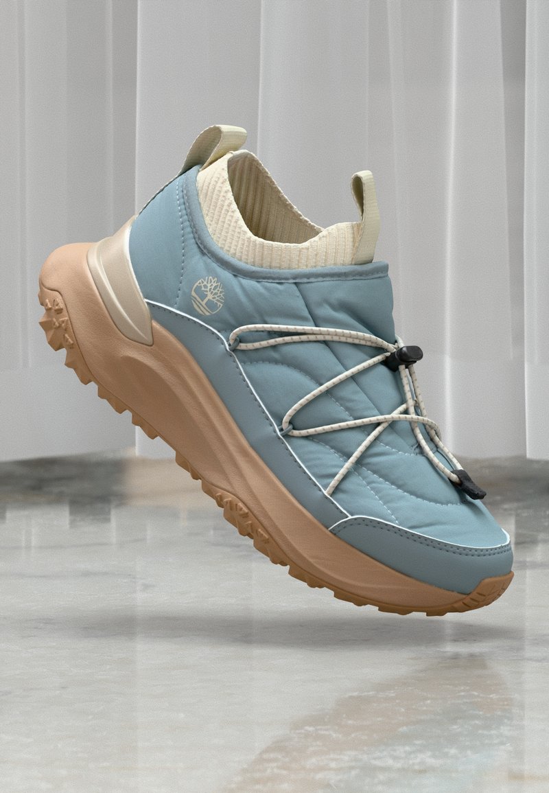 Lys blå quiltede sneakers med en beige gummisål, med elastiske snørebånd og en ribbet strikkrage. Logoet er preget på siden.