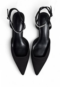 Melnas, piezīmētās smailes kurpes ar satīna apdari, atvērta aizmugure un plāni potīšu siksniņas, kas rotātas ar mazām rhinestone. Sadrumstalota tekstūra uz iekšējās zoles.