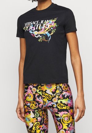 Camiseta de algodón negra con un diseño gráfico floral que presenta colores vibrantes y el texto "VERSACE JEANS COUTURE" destacado de manera prominente.
