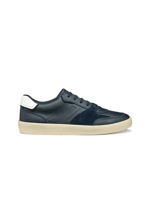 Zapatilla de color azul marino con paneles de cuero y ante, puntera redonda, acento blanco en el talón y suela de goma beige. Presenta detalles perforados.
