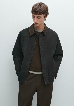 Dark brown jacket with a contrasting collar, snap buttons, and a relaxed fit over a brown sweater. Smooth material with no visible patterns.