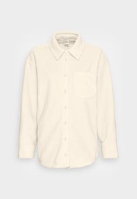 Camisa de botão branca em fleece com colarinho, mangas longas e um bolso no peito. Apresenta um corte descontraído e uma textura suave.