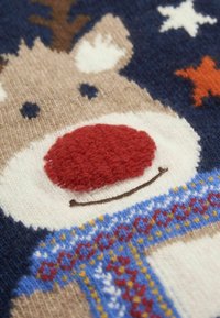 Sweter z włóczki z motywem renifera, posiadający czerwony, teksturowany nos, biały pysk, brązowe rogi oraz kolorowe, dziane akcenty na ciemnym tle.