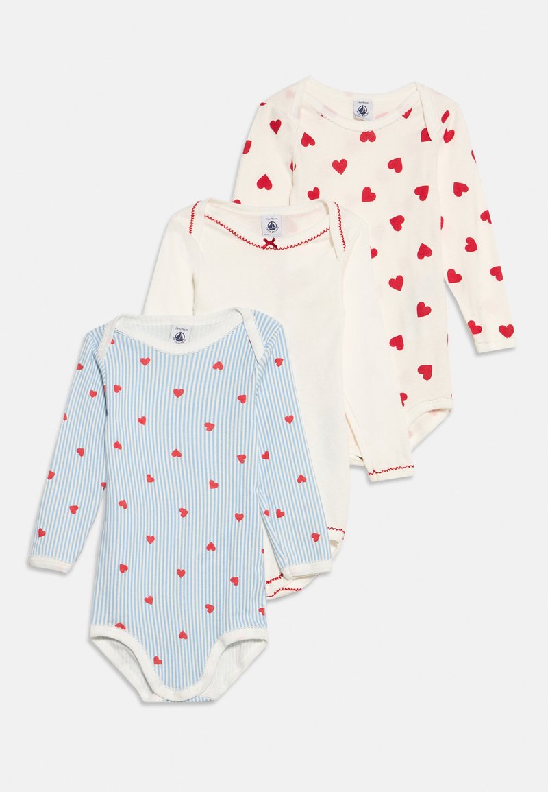Trois bodies bébé à manches longues, deux blancs avec des motifs de cœurs rouges, un rayé bleu et blanc avec de petits cœurs rouges.