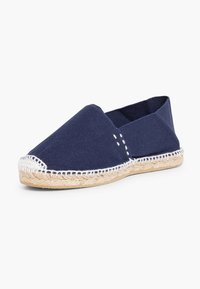 Marine canvas espadrille met een wiggenzool van jute, met witte stiksels langs de rand en uitsparingen aan de zijkanten voor ademend vermogen.