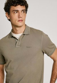 Khaki polo shirt lavet af bomuld, med foldet krave, to-knaps lukning og diskret logo broderi på brystet.