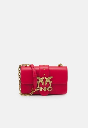Rote Leder-Schultertasche mit goldener Kette als Träger und goldenem verschluss in Vogel-Form mit dem Markennamen "PINKO" vorne.