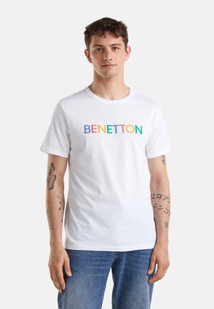Camiseta de algodón blanca con el texto multicolor "BENETTON" en el pecho. Mangas cortas y cuello redondo. Corte casual.