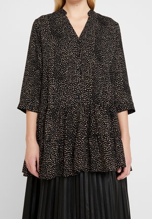 Tunic nera con pois rosa, scollatura a V, maniche a tre quarti, orlo arricciato, realizzata in tessuto leggero. Bottoni lungo la parte anteriore.