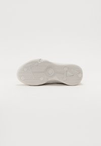 Hvid sneakersål med tekstureret gummi, der har et fiskebensmønster for greb. Rund hæl og cirkulære detaljer nær midten.