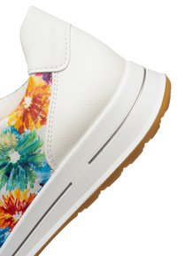White sneaker heel with textured sole and colorful floral pattern on the upper side near the ankle.