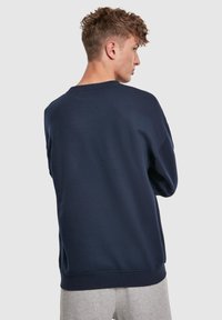 Felpa blu navy con collo a giro e maniche lunghe, realizzata in tessuto morbido, con polsini e orlo a costine, vista dal retro.