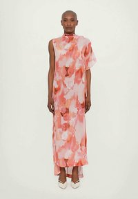 Dolge, roza cvetlične obleke z abstraktnimi akvarelnimi vzorci, lahkotna tkanina, asimetrična zasnova in stranski razporek, v kombinaciji z belimi čevlji.