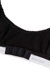 Bra in cotone nero con bordo ondulato, chiusura con ganci e occhielli e etichetta bianca del marchio sul sottobanda. Texture liscia su tutta la superficie.