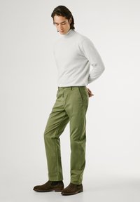 Gray turtleneck sweater, olive green trousers, and dark brown suede ankle boots. Trousers feature front pockets and a button closure.