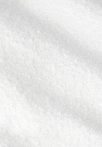 Close-up van fijne witte korrels met een iets onregelmatig oppervlak en zachte verlichting die textuurdetails toont.