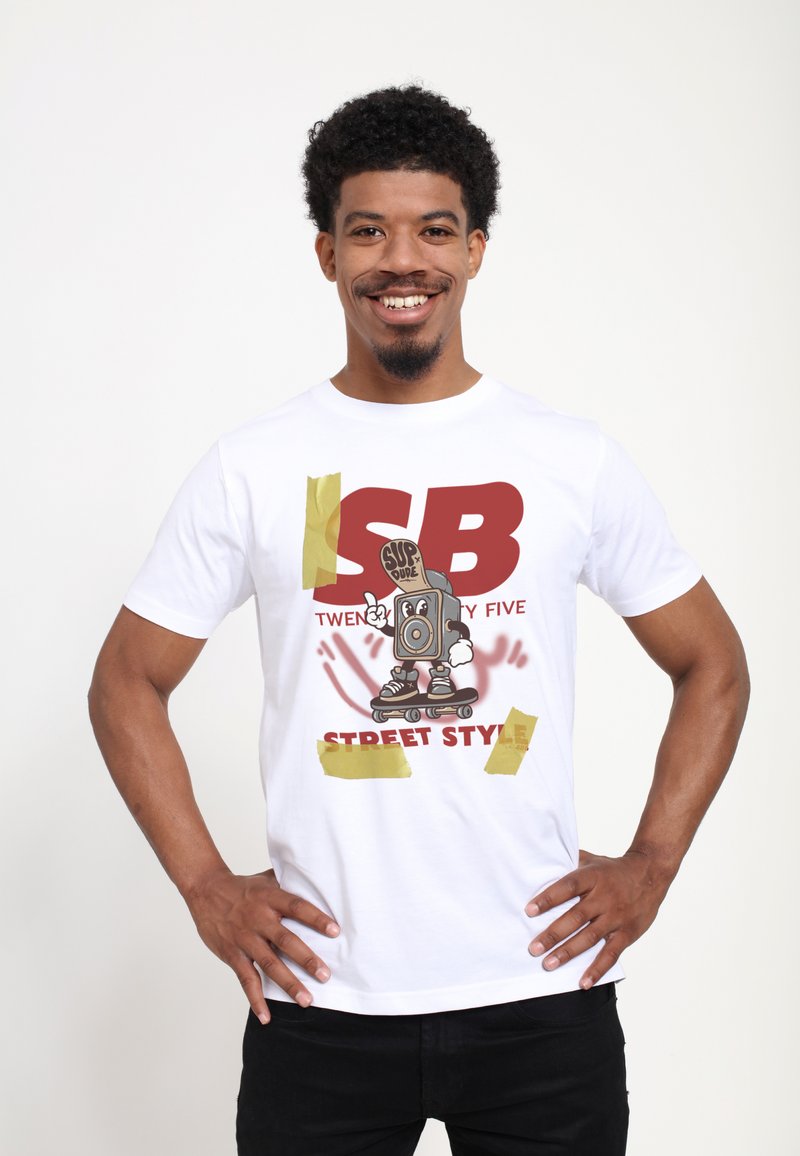 Bílý bavlněný tričko s kresleným motivem reproduktoru na skateboardu. Text zní "SB TWENTY FIVE STREET STYLE." Detaily zahrnují žluté pásky.