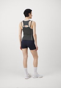 Σκούρο πράσινο αθλητικό μπλουζάκι με λευκές λεπτομέρειες, που διαθέτει σχέδιο με κοψίματα στην πλάτη. Συνδυασμένο με ναυτικές σορτς, λευκές κάλτσες και αθλητικά παπούτσια.