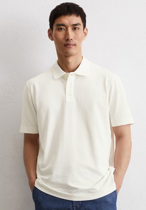 Polo shirt in gebroken wit, met een textuurmateriaal, korte mouwen en een drieknoopsluiting. Opvallend door het subtiele, geweven patroon.