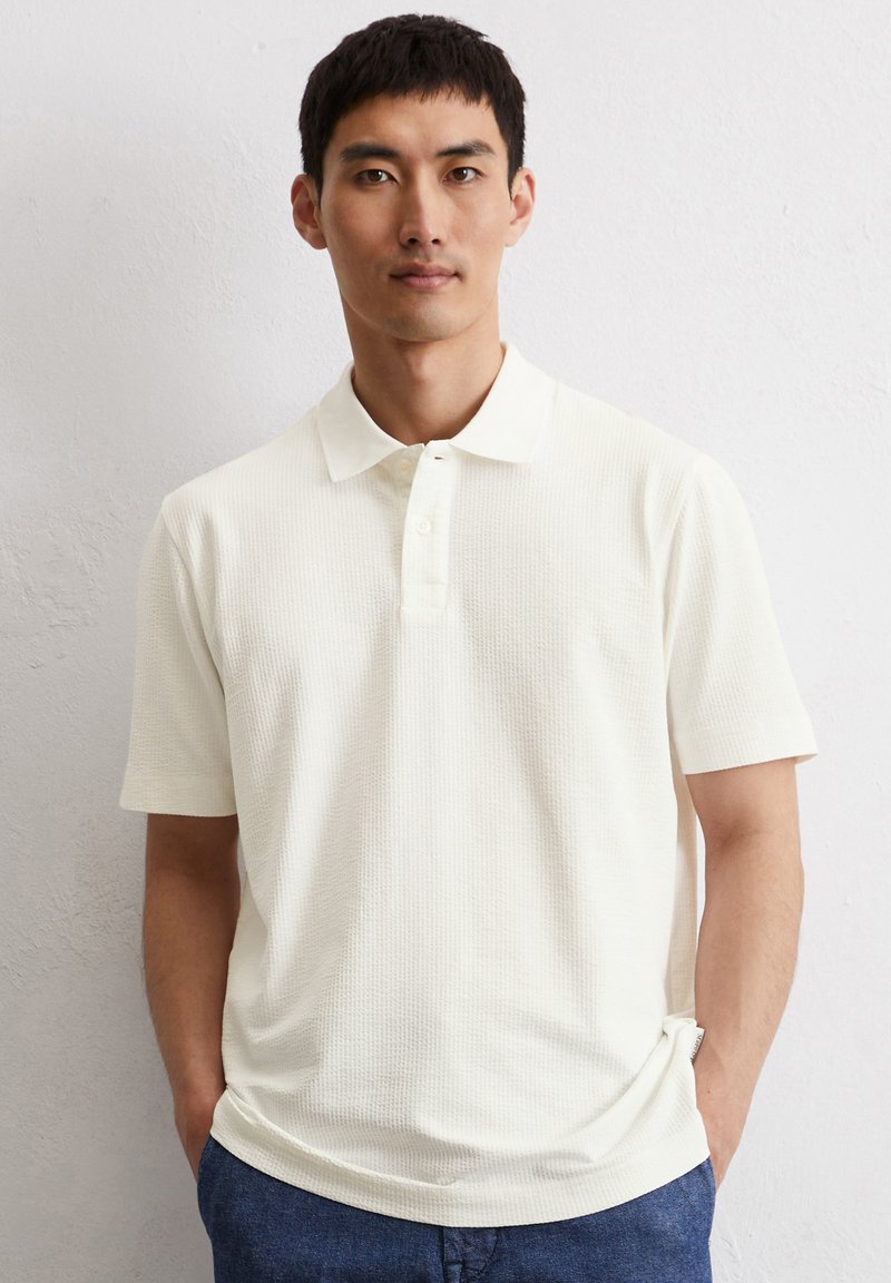 Polo shirt in gebroken wit, met een textuurmateriaal, korte mouwen en een drieknoopsluiting. Opvallend door het subtiele, geweven patroon.