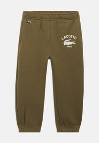 Calças de feliz verde-azeitona com cintura e punhos elásticos, apresentando o logo da Lacoste Paris e um pequeno emblema de crocodilo na frente.