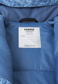 Niebieska wodoodporna kurtka wewnętrzna z miękkim polarowym wykończeniem, metka z nazwą marki "reima", rozmiar 104/4T oraz instrukcje pielęgnacji.