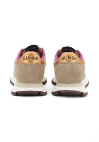 Beige suède sneakers met witte zolen, metallic bronzen hieltabs, paarse interieurs en "SUN68" gedrukt aan de achterkant.