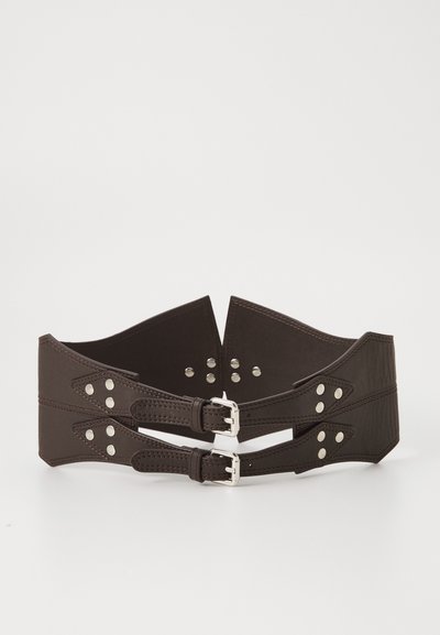 Cinturón de cuero marrón con dos correas, herrajes plateados y tachuelas decorativas. Presenta un diseño ancho con bordes puntiagudos y textura variada.