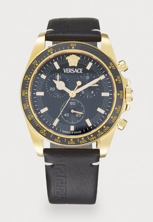 Gold-tone chronograph watch with a black leather strap. Features a black dial, gold accents, bold hour markers, and Versace logo.