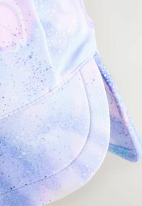 Kšiltovka s pastelovým motivem galaxie v odstínech fialové a modré, doplněná stříbrným třpytem a zakřiveným kšiltem. Měkký povrch.