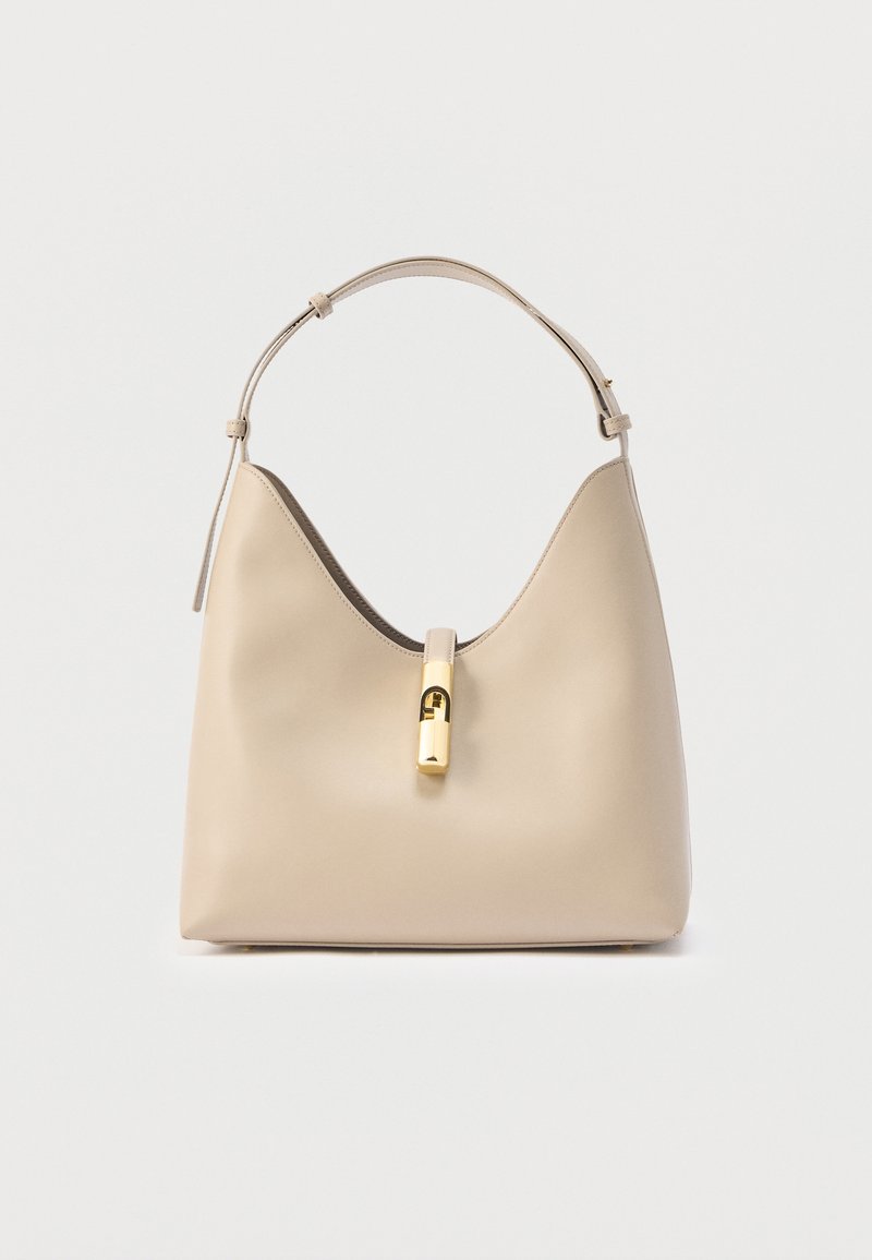 Μπεζ δερμάτινη τσάντα ώμου με έναν ρυθμιζόμενο ιμάντα και κεντρικό χρυσό κούμπωμα σε απλό φόντο.