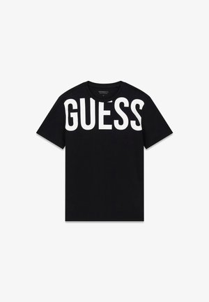 Camiseta negra de manga corta con gran texto blanco "GUESS" en el pecho superior y hombros.