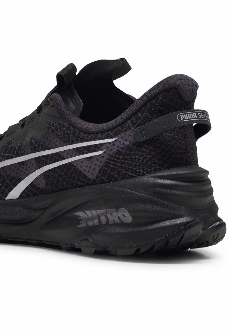 Chaussure de sport noire avec tige en maille texturée, accents contrastants violet foncé, semelle rembourrée et logo "NITRO". Design épuré avec une languette.