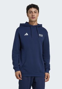 Marineblaue Kapuzenjacke mit einer vorderen Kängurutasche, verstellbarem Kapuzenzug und weißem Adidas-Logo, mit dem Aufdruck "BMW BERLIN MARATHON" auf der Brust.