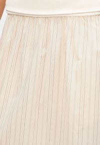 Φούστα ανοιχτού μπεζ χρώματος με κάθετες λεπτές γραμμές σε απαλούς τόνους. Διαθέτει ελαστική ζώνη με πιέτες, λεία υφή και ρέον ύφασμα.