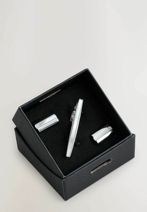 Ezüstszínű nyakkendőtű és mandzsettagomb szett, letisztult dizájnnal, sima, fényes felülettel, fekete díszdobozban, puha béléssel bemutatva.