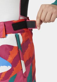 Pantalones de esquí multicolores con un audaz patrón abstracto en rojo, azul y verde; con una correa de cintura ajustable de velcro.