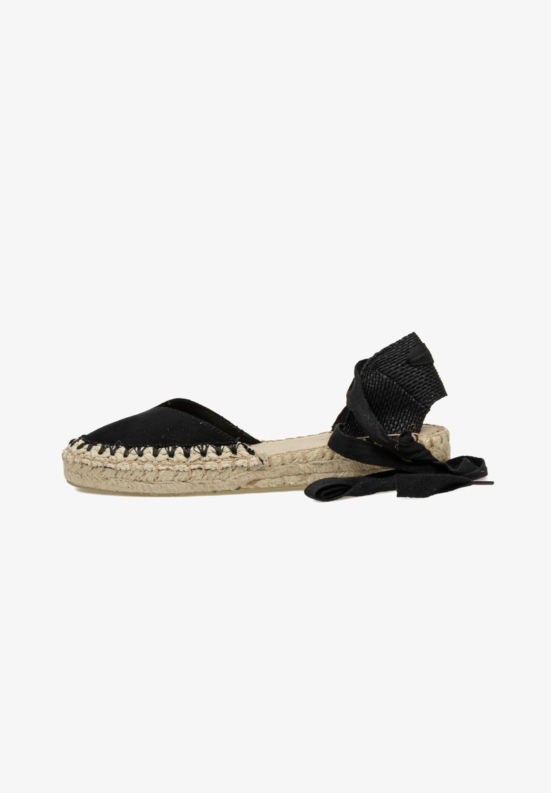 Espadrille negra con parte superior de lona, suela de yute y un borde trenzado. Presenta largas cintas negras alrededor del tobillo para un ajuste seguro.