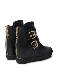 Stivali alla caviglia in pelle nera con cerniere e fibbie dorate, caratterizzati da una suola testurizzata e un marchio sul lato.