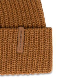 Bruine gebreide beanie met een geribd patroon en een omgeslagen manchet. Heeft een rechthoekig leren label met "HERSCHEL" in donkerbruin geperst.