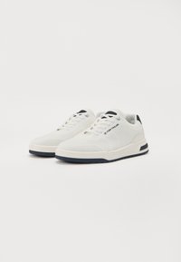 Hvite sneakers med en mesh overdel, teksturert design, kontrastfargede marineblå detaljer og en gummisåle med en lett konturert form.