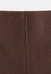 Gros plan sur un tissu en maille côtelée marron avec une couture verticale au centre.